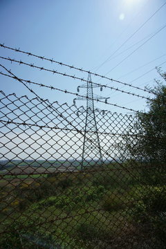 High voltage electricity transmission pylon behind fence