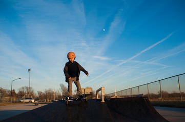 Young boy in helmet riding down pyramid ramp at skate park