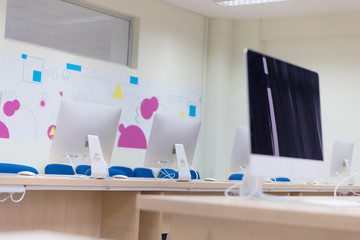 Modern office with computers on desks. Empty computer room in college. Interior of classroom with computers. Concept of corporate working space.