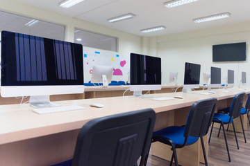 Modern office with computers on desks. Empty computer room in college. Interior of classroom with computers. Concept of corporate working space.