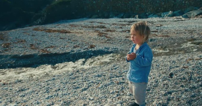 Little toddler walking by a stream on the beach