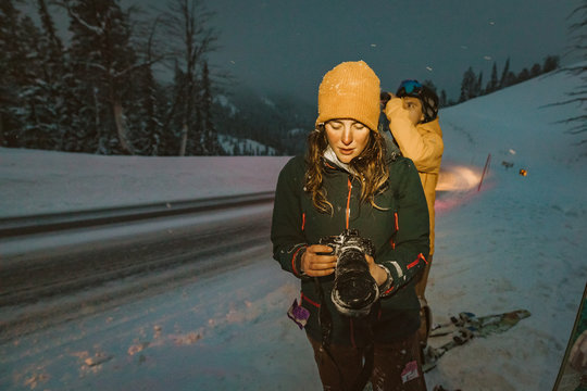 young photographer lady checks her camera after a snowy late ski