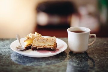 Sweet food - cup of tea or coffee and cake slice with chocolate, dessert on table