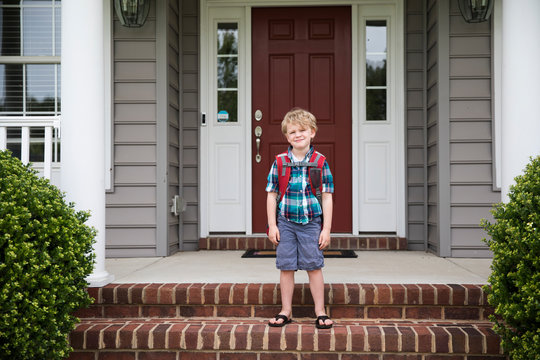 Cute Blonde Curly Headed Boy Waits For School Bus on Front Steps