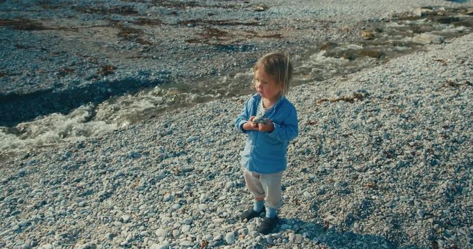 Little toddler standing by a stream on the beach