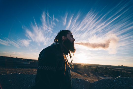 Rastaman smokes smoke through his mouth.
