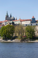 Obraz premium Spring green Prague Lesser Town with gothic Castle above River Vltava in the sunny Day, Czech Republic