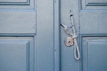 Porta antiga cinzenta com corda para abrir