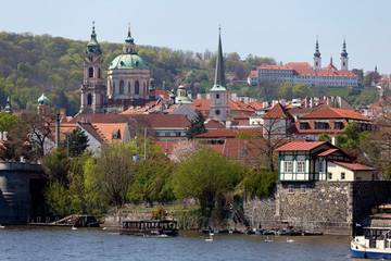 Spring green Prague baroque St. Nicholas' Cathedral with the Lesser Town above River Vltava in the...