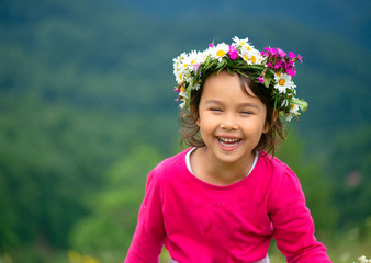 cute girl with flower crown smiling and having fun on meadow