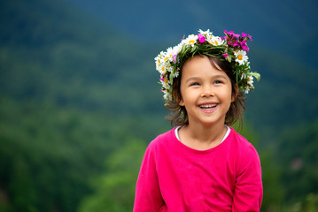 cute girl with flower crown smiling and having fun on meadow