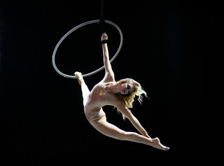 Graceful aerial acrobat doing her performance with a hoop isolated on black © Hladchenko Viktor