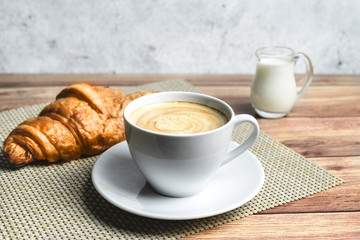 Perfect breakfast of croissant and coffee on wooden table. Rustic style.