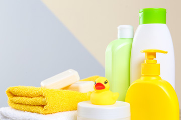 Baby cosmetic products, toy and towels against color background, closeup