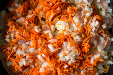 Cooking for soup, chopped carrots and onions are fried in a pan
