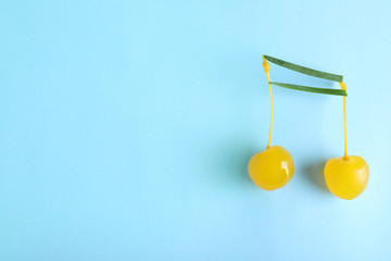 Musical note made of onion and cocktail cherries on color background, top view. Space for text
