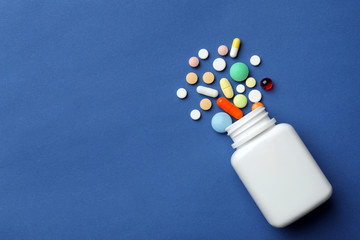 Bottle with different pills on color background, flat lay. Space for text