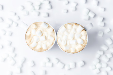 Romantic desk top with two cups of coffee with marshmallows on marble table. Top view.