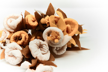 Bouquet of flowers made of couche gift paper insulated on a white and blurred background.