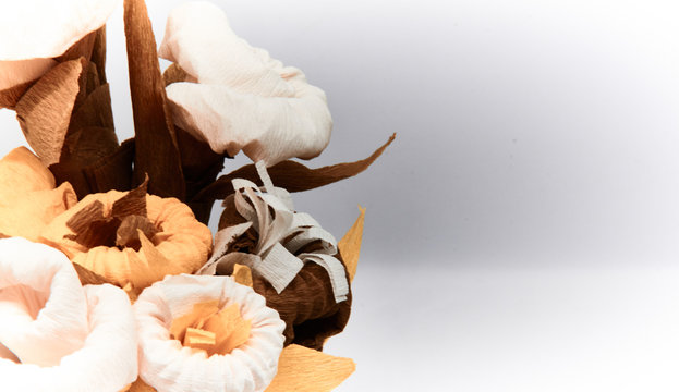 Bouquet of flowers made of couche gift paper insulated on a white and blurred background.