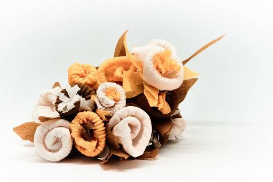Bouquet of flowers made of couche gift paper insulated on a white and blurred background.