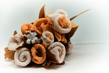 Bouquet of flowers made of couche gift paper insulated on a white and blurred background.