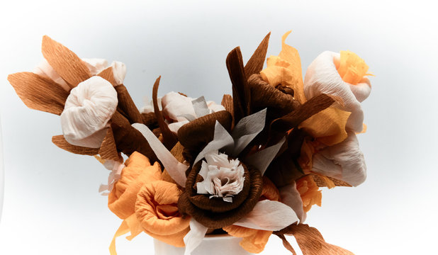 Bouquet of flowers made of couche gift paper insulated on a white and blurred background.