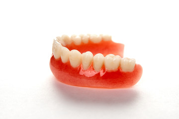 Fototapeta premium Artificial teeth on a white background with copy space, close-up