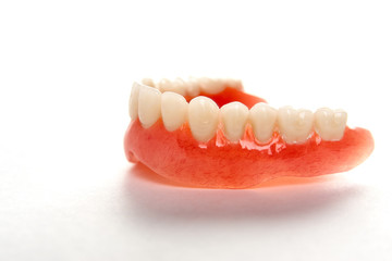 Artificial teeth on a white background with copy space, close-up