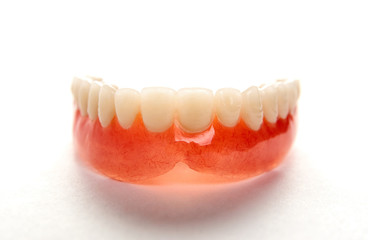 Artificial teeth on a white background with copy space, close-up