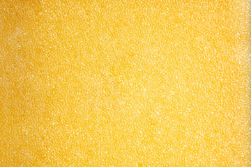 Yellow sponge texture background, close-up. Shiny soft sponge