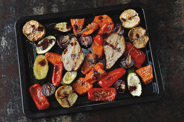 Baked vegetables and fruits on a baking sheet. Vegan theme. Appetizing baked vegetables and fruits with spices.