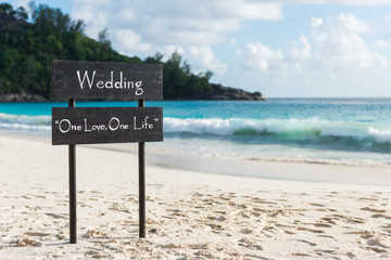 Black wooden plate with wedding sign at beach