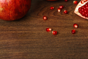 red pomegranate fruits and seeds on a dark surface