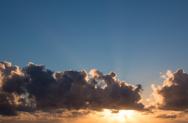 Sunrise with blue sky and sun behind the clouds