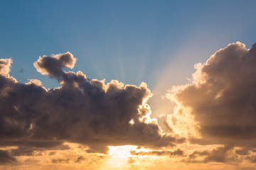 Sunrise with blue sky and sun behind the clouds