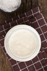 Fresh homemade bubbly sourdough starter, a fermented mixture of water and flour to use as leaven for bread baking, photographed overhead (Selective Focus, Focus on the top of the starter)