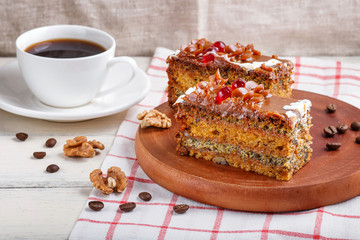 a piece of cake with caramel cream and poppy seeds on a wooden kitchen board and a cup of coffee, white background..
