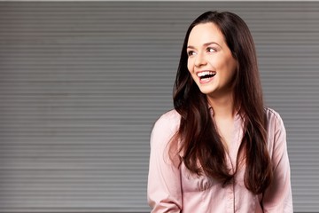 Portrait of pretty young woman in pink shirt on grey background