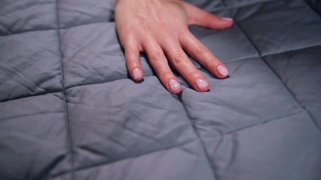 Female hand touching soft and clean grey blanket.