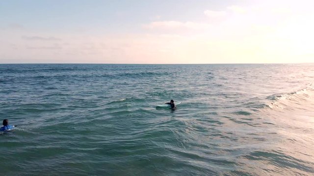 Cinematic drone / aerial rotating footage showing a couple of surfers at Cole Harbour coast in Lawrencetown, Nova Scotia, Canada during summer season.