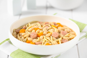 Chilean Porotos con Riendas (beans with reins) dish of cooked dried beans with pumpkin, onion, spaghetti and sausage, photographed with natural light (Selective Focus, Focus one third into the dish)