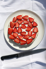 Gluten free almond sponge cake decorated with whip cream and strawberries. Top view.