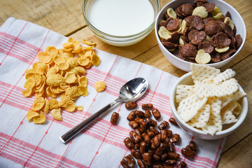 Breakfast Cornflakes and various cereals in bowl and milk cup on wooden background for cereal healthy food in the morning