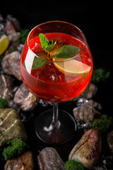Aperol syringe soft alcoholic drink on a black background with stones and ice. Cocktail card for a bar or restaurant.