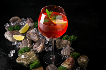 Aperol syringe soft alcoholic drink on a black background with stones and ice. Cocktail card for a bar or restaurant.