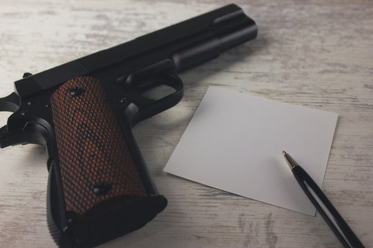 a gun and a note on a wooden table