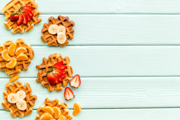 Traditional belgian waffles with fruit topings on mint green wooden background top view mock up