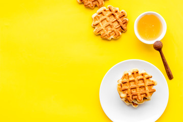 Homemade Viennese waffles with honey and flatware on yellow background top view make-up