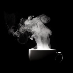 Steaming coffee in cup isolated on black background with copy space.